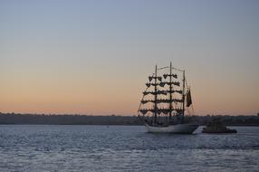Ship on the water with ripple, among the trees, at colorful and beautiful, gradient sunset