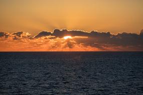 sun behind the clouds on the sea horizon during dawn