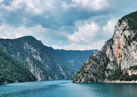 Beautiful landscape of the lake among the mountains with green plants, under the clouds, in Montenegro