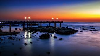 pier with glowing lanterns on the coast at night