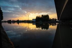 Beautiful landscape of the water coast with silhouettes and reflections, at colorful and beautiful sunset with clouds