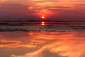 the setting sun on a red sky over the sea