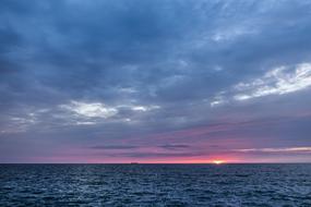 pink sunset in the clouds over the ocean horizon
