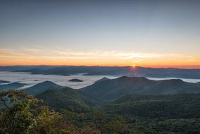 sun on the horizon behind the mountains during sunrise