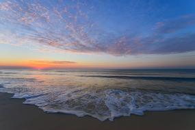 sunset over the sea surf on the sand