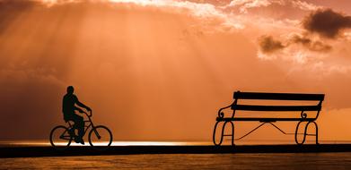 silhouette of a cyclist on the embankment at sunset