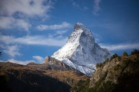 Beautiful landscape with snowy Matterhorn and other colorful mountains in Switzerland, under the blue sky with clouds