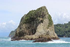 rock in the ocean on a clear day