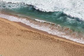 Beautiful landscape of the sandy beach with colorful waves of different shades