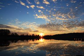 Beautiful landscape of the lake, with reflections of the trees, in Germany, at colorful and beautiful sunset, among the clouds