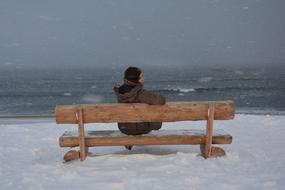 girl sitting on a bench near the sea in winter