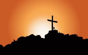 silhouette of a large cross on a hill at dusk