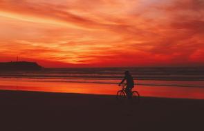 Silhouette of the bicycle rider on the beach, at colorful and beautiful sunset