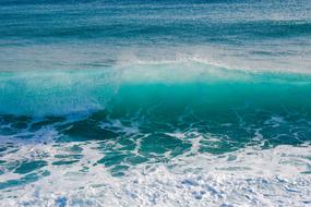 Close-up of the beautiful, turquoise wave in the sea, with foam