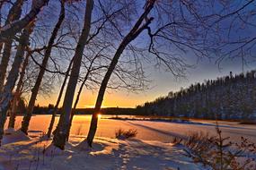 Beautiful winter landscape with the frozen lake, among the trees, in Quebec, Canada, at colorful and beautiful sunset