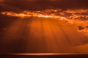 sunset rays in the clouds over the water at dusk