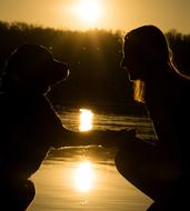 Silhouette of girl and dog at Sunset