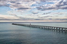 gray clouds over a long pier in the ocean