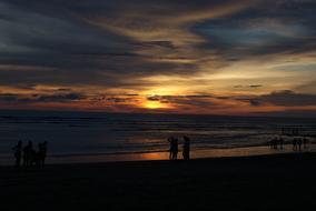 silhouettes of people on the beach in bali at dark twilight