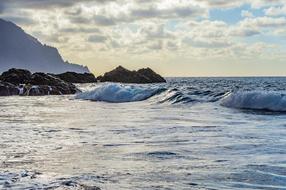 Beautiful landscape of the beach with rocks and waves, at colorful and beautiful sunset with clouds