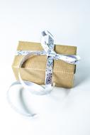 Beautiful Christmas gift box with shiny ribbon, on the white surface, in light