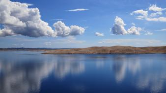 white clouds reflected in blue water in croatia