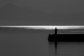 Silhouette of the lighthouse, on the coast of the sea, at beautiful sunrise