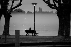 distant view of a man on a park bench in monochrome