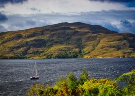 sailboat on the sea near the green hills