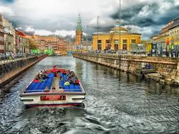 Colorful boat on the canal in beautiful Copenhagen, Denmark, under the clouds