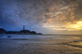 distant view of the lighthouse on the ocean coast at dusk