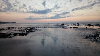 Beautiful landscape of the sea with rocks, in Normandie, France, at colorful and beautiful sunset with clouds