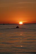 Fisherman on the boat, on the sea, at colorful and beautiful sunset