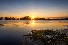 Beautiful landscape of the lake, among the trees, at colorful and beautiful sunset on horizon