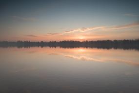 pink Sunset over dark forest near calm water