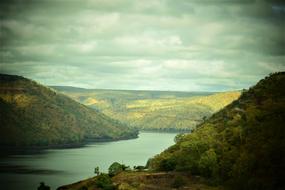 Beautiful landscape of the river, among the colorful mountains, under the clouds