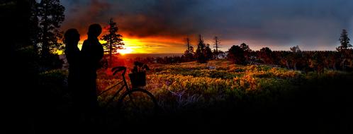silhouette of romantic couple with bicycle at sunset
