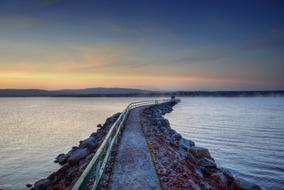 beautiful Sunset over long pier at calm Lake