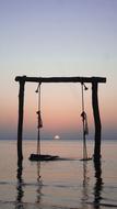 Silhouette of the swing above the sea with ripple, at colorful and beautiful, gradient sunset