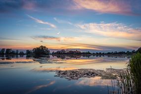 Beautiful landscape of the lake with reflections, among the trees, at colorful and beautiful sunset among the clouds