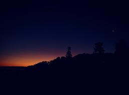 silhouette of a hill against a purple sky during sunset