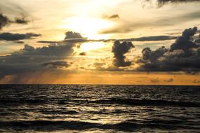 sunset in the clouds over the sea waves