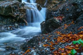 waterfall on rocks with yellow leaves