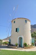 Beautiful landscape with the windmill, among the plants, in sunlight, on Crete, Greece, under the blue sky