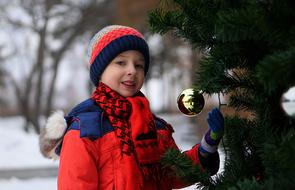 child near the christmas tree on the street