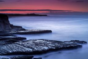 Beautiful landscape of the seashore with rocks, at colorful and beautiful, gradient sunset in the sky