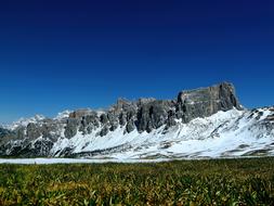 Beautiful, snowy Cima Ambrizzola near the plants, on Dolomites in Italy, under the blue sky