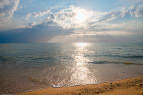 Beautiful beach of the sea in sunlight, among the clouds in the blue sky