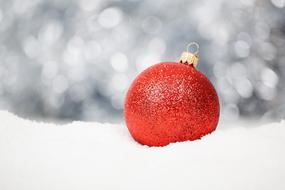 red christmas ball on snow on blurred background