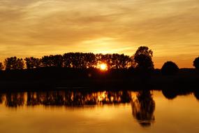 Beautiful West Lake with silhouettes of the plants on the shore, at colorful and beautiful sunset among the clouds